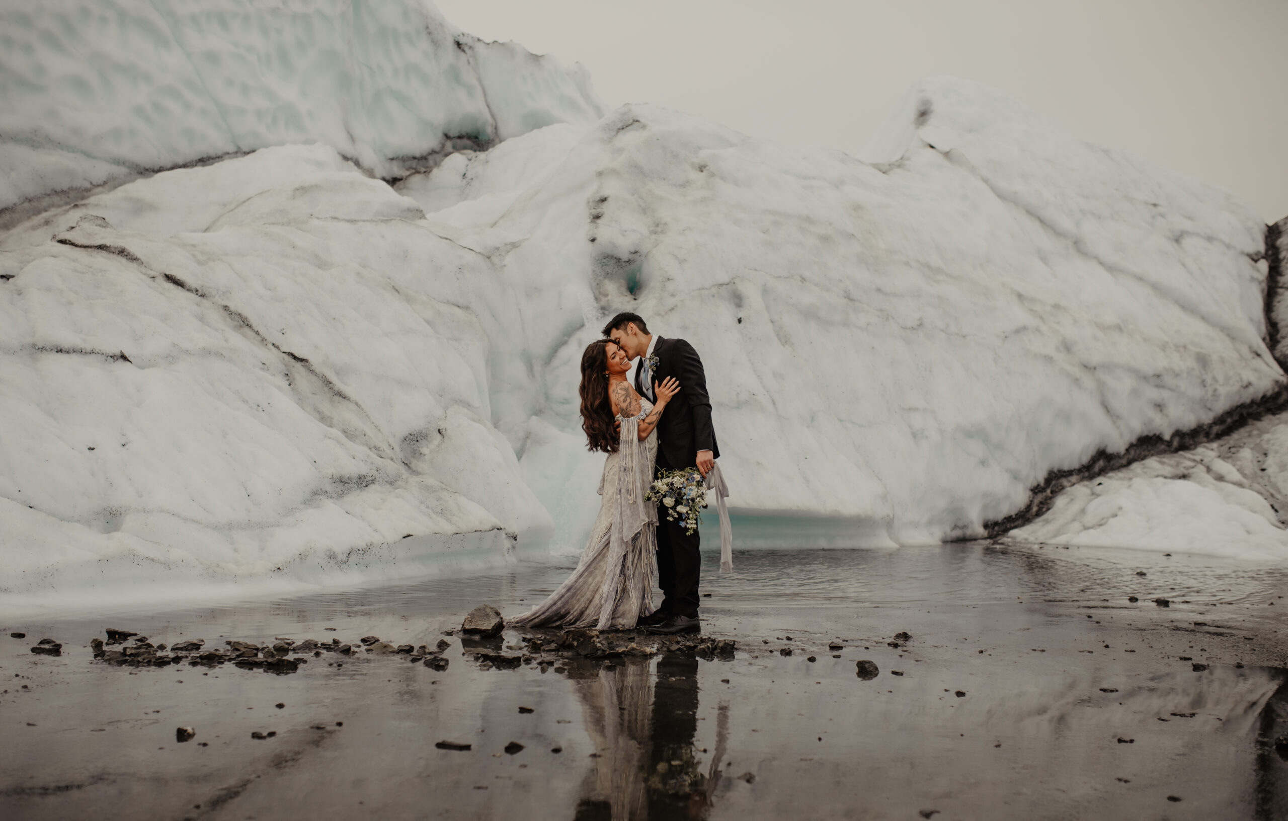 Couple Cuddling Close while Man kisses Woman on Cheek after Elopement on Blue and White Alaskan Matanuska Glacier
